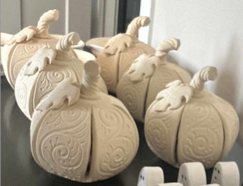 Group of unglazed ceramic pumpkins showing detailed hand-sculpted ornament