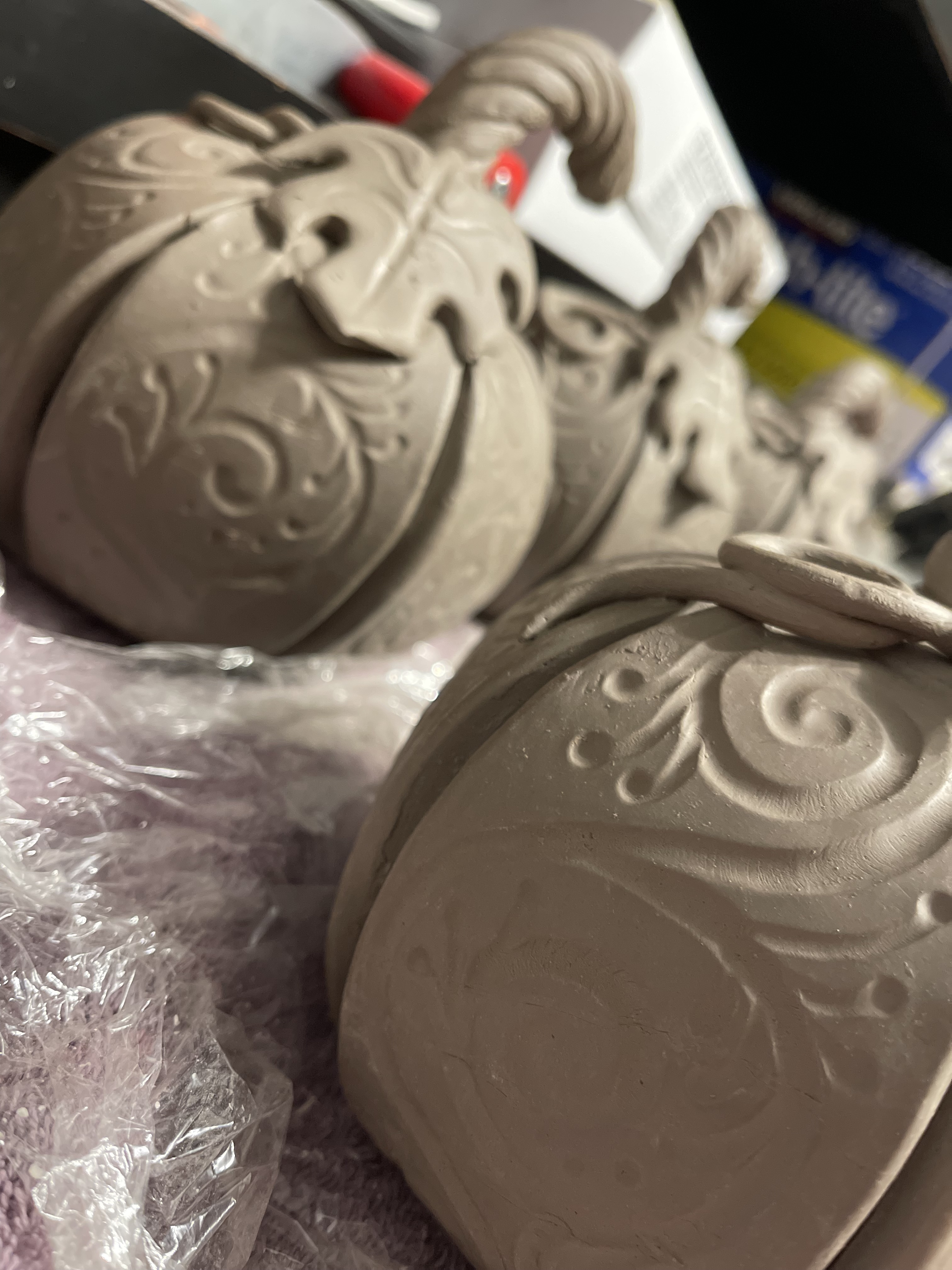 Close-up of unglazed ceramic pumpkins with handmade filigree and leaf details