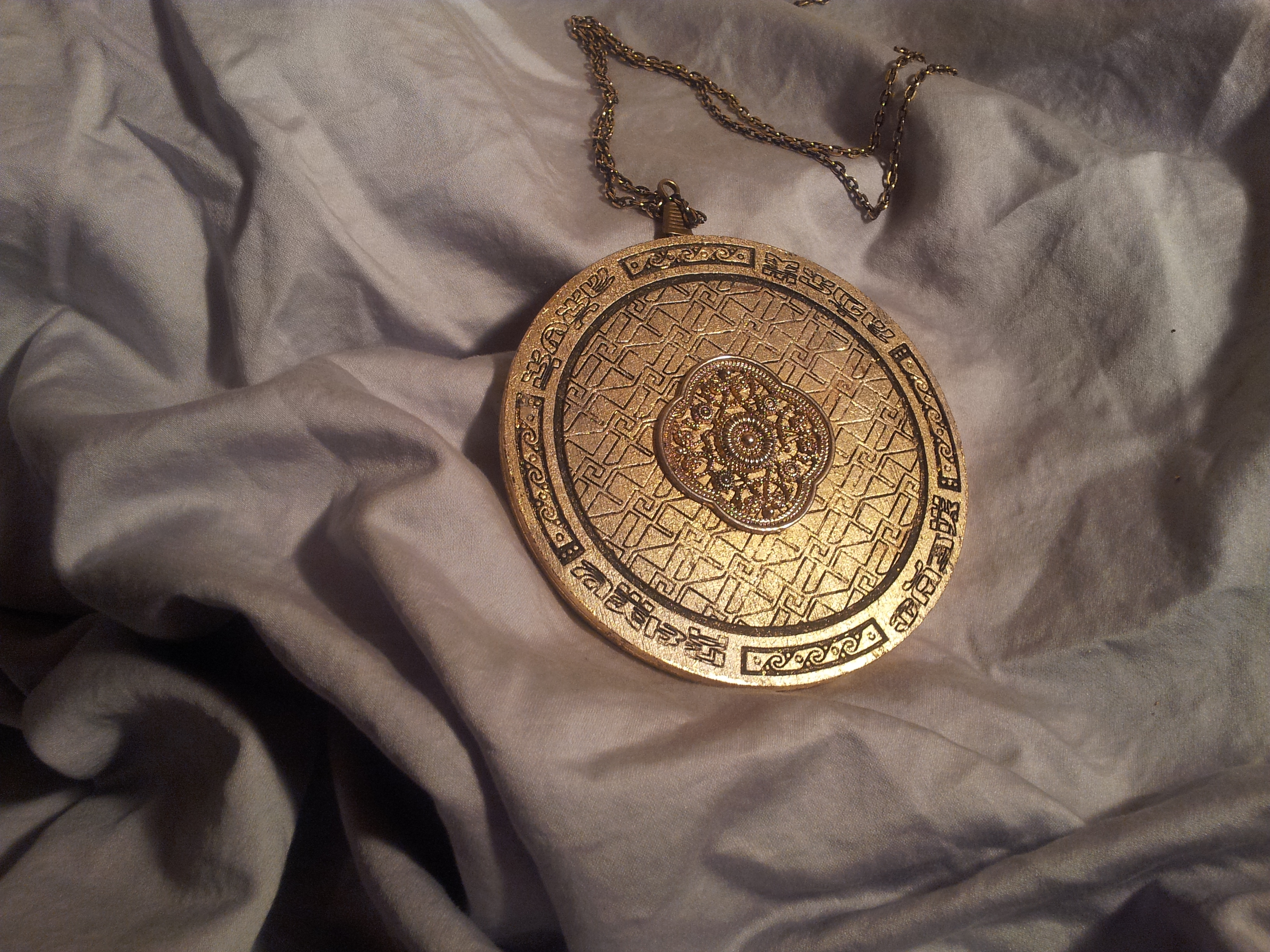 Completed circular Secret King medallion suspended from a cord