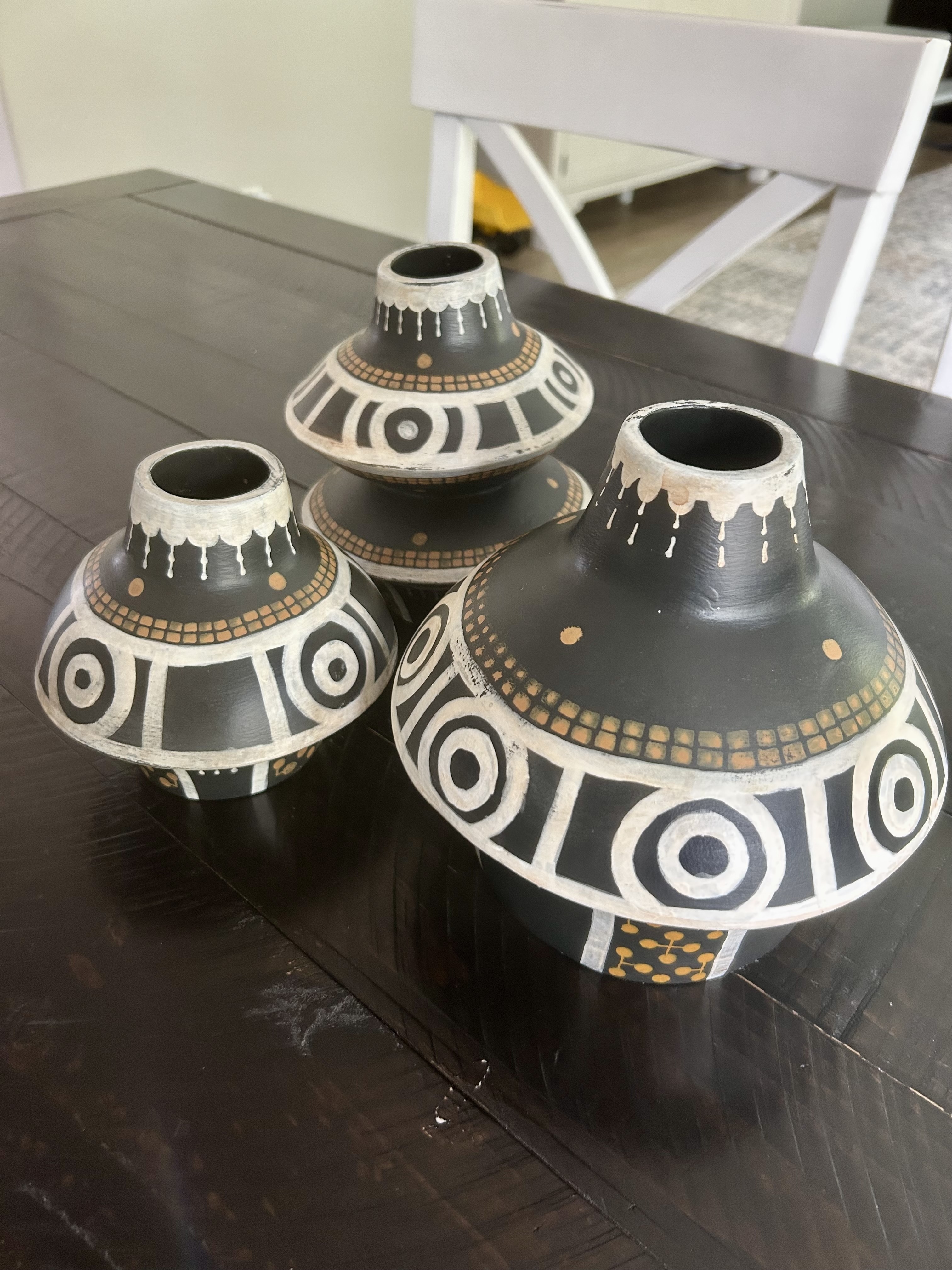 Three black ceramic jugs decorated with white and yellow geometric patterns