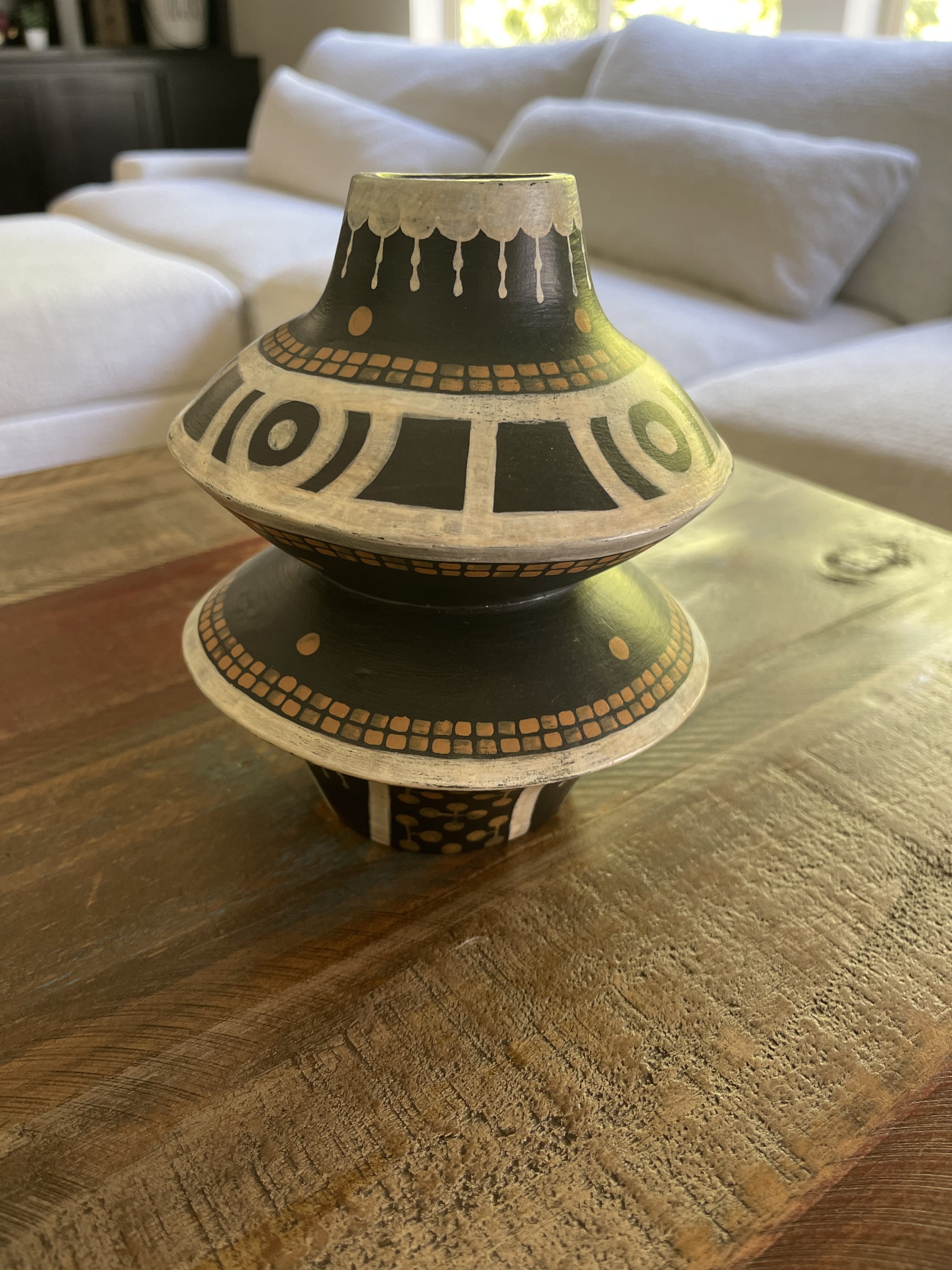 Side view of a black ceramic jug with flared shoulder and geometric decoration